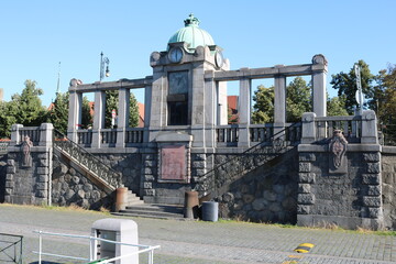 An old pier with a clock on the Vltava embankment in Prague against the blue sky on a sunny day