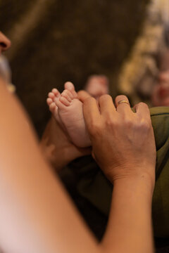From above of crop anonymous mon massaging small feet of adorable barefoot baby lying on bed in sunny morning
