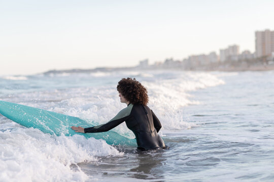 Smiling woman in wetsuit with surfboard in waving sea