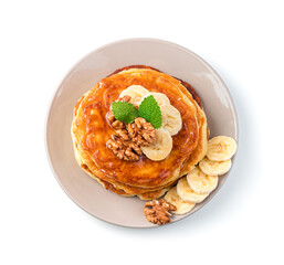 Pancakes with banana, nut and mint in a beige plate isolated on white.