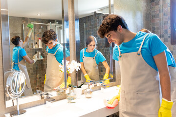 Young cleaning crew washing bathroom during work in modern apartment
