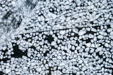 abstract texture of broken white ice and dark blue water. View of the ice from a drone. background of the frozen surface of a clean lake or river