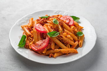 Penne pasta with bolognese sauce on a gray background. Italian cuisine.