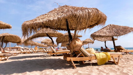 holiday resort white sand beach straw women hats awnings umbrellas blue sky wooden tables sun...