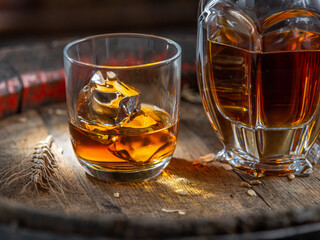 Carafe of whisky and glass of whisky on old wooden cask at the dark background.