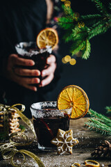 Woman in black festive dress holding glass of Swedish glögg on dark background. Traditional Nordic...