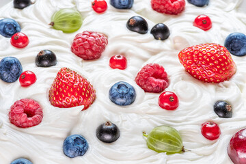 Mix of fresh berries in the yoghurt or cream. Top view.