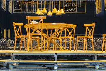 Yellow wooden chairs and table on the theater stage with a dark background
