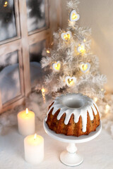 Christmas cake with raisins. White background Christmas tree, two burning candles. Traditional bundt cake. Vertical photo.