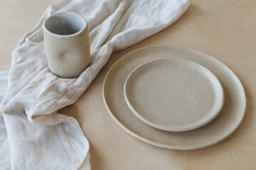 Obraz na płótnie Canvas Beige ceramic plate on a wooden table top view. minimalist handmade ceramic tableware and pottery.