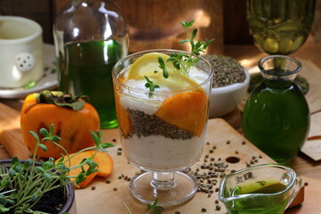 Obraz na płótnie Canvas Dessert with yogurt, persimmon and hemp sativa sprouts on wooden background