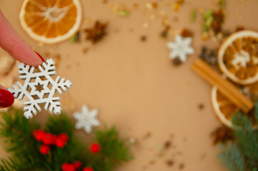 Decorative snowflake in female hands on blurred background of winter composition with copy space. Star anise, spruce branch, rowan, dried orange, spices, cinnamon stick.