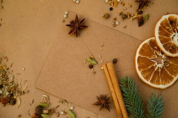 Fototapeta na wymiar Christmas and New Year's background with copy space. Vintage envelope with letter lying on table with star anise, spruce branch, dried orange, spices, cinnamon stick.