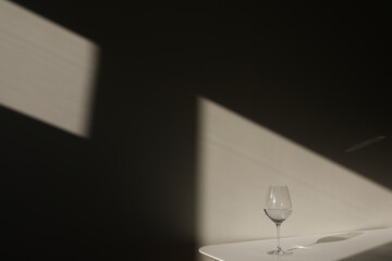  A glass of water on a white background with a shadow. Chiaroscuro from the window. Close-up, copy...