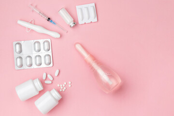 Gynecology concept. Vaginal suppositories, enema, tablets, applicator on pink background, treatment...