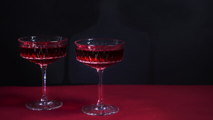 Two red wine glasses on a black background with copy space for your text.tempting offer advertising red wine. wine list. restaurant advertising. a bright combination of red and black. romantic dinner