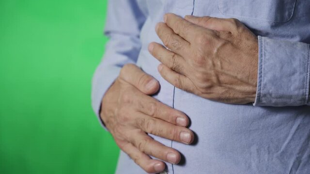 Hands of an elderly person on the stomach. Pain in the abdomen. Green background