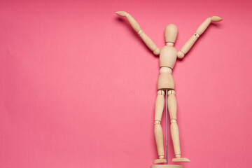 wooden mannequin on pink background posing close-up