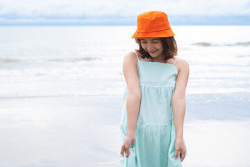 young pretty woman looking and walking on the beach ocean at tropical beach, enjoy her freedom and fresh air, wearing stylish hat and clothes. Outdoor summer portrait.