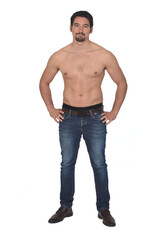 man shirtless and with blue jeans, hands on hip and  looking at camera on white background