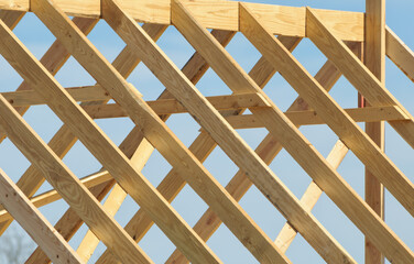 Roof under contruction, with wooden trusses against partly cloudy sky