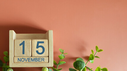 November 15, Date design with calendar cube and leaf on orange background.