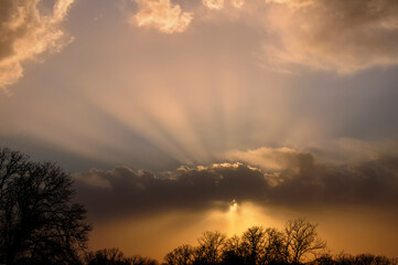 Dramatic storm clouds in the evening, with sun rays shining through the clouds near sunset