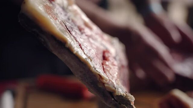 Close up shot of dried pork carcase on background of working butcher, man preparing dried and smoked meat for sales. Dried and smoked meat production