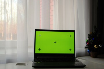 Merry Christmas and Happy Holidays. Green laptop screen on the table