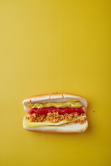Hot Dog with mustard and ketchup over yellow background