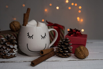 Christmas cocoa with marshmallows and cinnamon in a white cup with a smile, top view. coffee cup with homemade hot chocolate. Photo of a winter drink on a light background