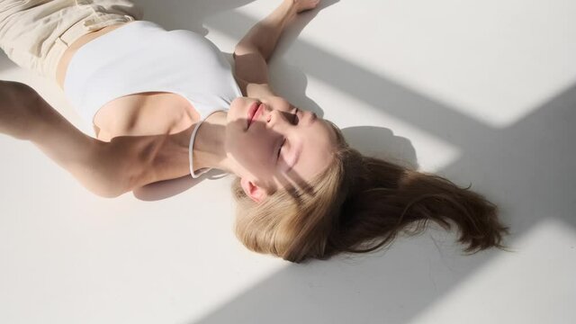 Beautiful woman lying on floor with eyes closed over white background