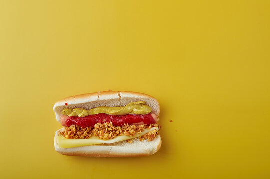Hot Dog with mustard and ketchup over yellow background