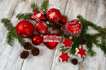 Ein Arrangement mit rotem Christbaumschmuck, Tannenzweigen und -zapfen angeordnet auf hellen...