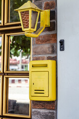 An old yellow mailbox and street light hanging on the street at the entrance to a residential building