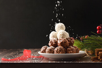 Coconut and chocolate balls and shavings falling dark background front
