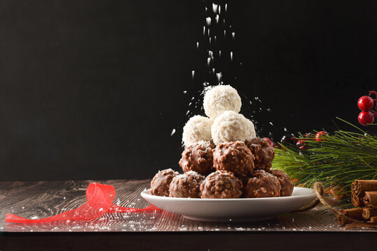 Coconut And Chocolate Balls And Shavings Falling Dark Background Front