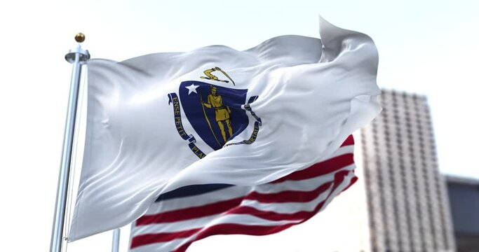 the flag of the US state of Massachusetts waving in the wind with the American flag blurred in the background