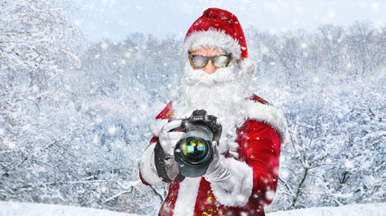 cool Santa Claus taking holiday pictures in the snowy landscape - obrazy, fototapety, plakaty