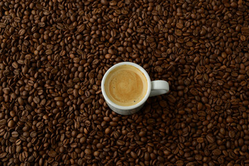 A cup of coffee on the background of coffee beans. Fresh fragrant black coffee in a white coffee cup on the background of natural coffee beans, copy space