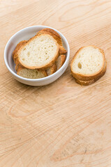 white stoneware bowl with fresh organic sliced bread on a rustic wooden background