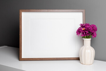 Blank landscape frame mockup over grey wall with fresh chrysanthemum flowers.