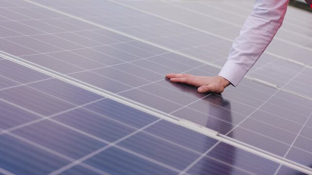 Closeup to the camera ecological engineer hands checking the operation of sun and cleanliness of photovoltaic solar panels concept of ecological innovation nature environment