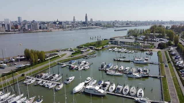 Antwerp marina Linkeroever yacht club drone fly over aerial shot with Antwerp skyline and river Scheldt with barges in the backgound.