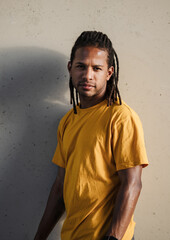 A vertical portrait of a dominican man with dreadlocks and yellow tshirt