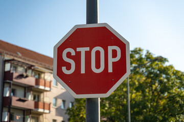 A stop sign in front of a tree and a residential building on a sunny day. Traffic symbols in a...