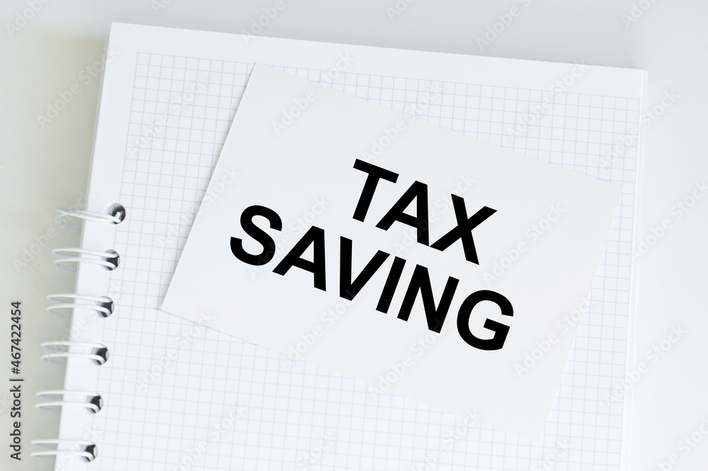 Poster white card with text tax saving on notepad on table, business concept