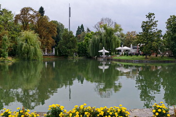 View of a cosy relaxation area under awnings with tables and chairs on the shores after rain of Lake Ariana, Borisova Gradina Park, Sofia, Bulgaria 