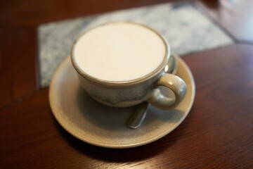 Latte coffee in a cup on a saucer, with a spoon.