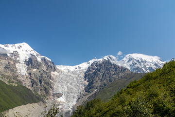 A panoramic view on the snow-capped peaks of Tetnuldi, Gistola, Lakutsia and the Adishi Glacier in the Greater Caucasus Mountain Range in Georgia, Svaneti Region. Sharp peaks, wanderlust, solitude.